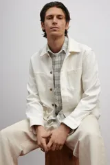 Sobrecamisa color crema en tejido texturizado de algodón, corte estándar, con cuello inglés, tapeta lisa, bolsillos superiores abiertos, canesú en la espalda, mangas largas con puños abotonados y bajo recto.