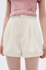 Short color crudo de poliéster, tiro alto, corte holgado y ruedo con dobladillo.