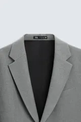 Blazer straight fit color gris confeccionada en tejido con viscosa. Cuello con solapas de muesca y manga larga acabada en puño con botón. Bolsillo de vivo en pecho y bolsillos de plastrón en cadera. Bajo con aberturas en espalda. Cierre frontal de botonadura.