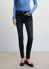 Jeans de tiro bajo color azul oscuro, corte skinny, cinco bolsillos, trabillas y cierre de cremallera y botón.
