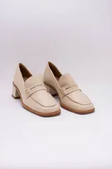 Mocasines clásicos de cuero color beige con taco cuadrado y detalle de antifaz.