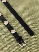 Cinturón negro de cuero vacuno con apliques metálicos plateados y hebilla metálica con diseño exclusivo.
