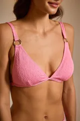 Top de bikini rosado con textura arrugada y detalles de aros dorados en los tirantes y en la bombacha.
