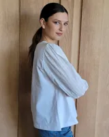 Remera blanca de algodón con mangas 3/4 abullonadas y cuello redondo. Presenta costuras a contratono en ruedo y cuello.