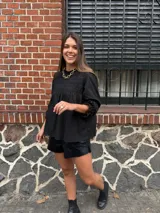 Camisa blanca de mangas largas con detalles de encaje en el cuello y el pecho.