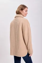Sobrecamisa color beige de textura sherpa, con cuello clásico, cierre frontal con botones a tono, bolsillos de parche con solapa en el pecho y corte recto.