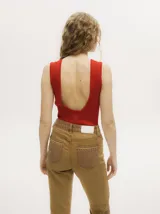 Body acanalado color rojo, de corte cavado con cuello a la base y espalda baja y abierta. Cierre inferior con botones a presión.