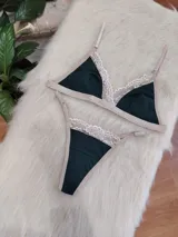 Conjunto de lencería de algodón color verde inglés con detalles de encaje nude, compuesto por un bralette de corte triangular con breteles regulables y una tanga con laterales ajustables.