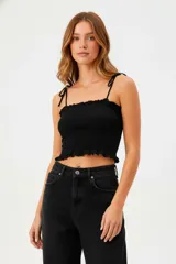 Top negro de algodón con breteles finos, punto smock, corte al cuerpo y cuello strapless.