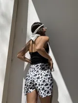 Short de denim elastizado con estampado animal print de vaca en blanco y negro, con bolsillos frontales de parche en color negro. Tiro alto y corte ajustado.