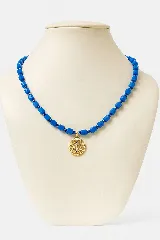 Collar de cuentas facetadas color azul eléctrico con dije circular dorado con incrustaciones de cristales azules.