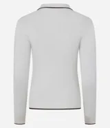 Blusa blanca de punto con cuello polo y mangas largas. Presenta detalles contrastantes en negro en el cuello, la abertura frontal y el dobladillo.
