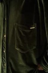 Camisa beige de terciopelo con cuello clásico, cierre frontal con botones, dos bolsillos de parche en el pecho y mangas largas con puños abotonados.