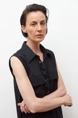 Vestido negro sin mangas con cuello camisero y cierre frontal con cordones. Presenta dos bolsillos con solapa a la altura del pecho y dos bolsillos laterales a la altura de la cadera.