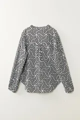 Camisa de manga larga con estampado geométrico en blanco y negro, cuello mao y cierre parcial con botones.