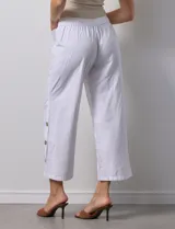 Pantalón blanco de algodón con pretina elastizada, bolsillos inclinados y ruedo con botones.