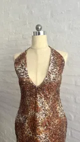 Vestido corto con estampado animal print en tonos marrones y blancos, con escote halter pronunciado y espalda descubierta.