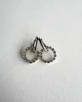 Par de aros colgantes con argollas doradas y dijes circulares de resina transparente con incrustaciones de strass de colores. El dije mide aproximadamente 1.5cm de diámetro.