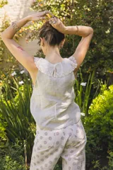 Blusa color crema sin mangas, confeccionada en lino liviano, con cuello redondeado de tul bordado con flores.