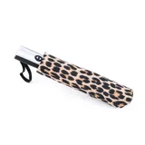 Paraguas automático con estampado de leopardo, mango plateado y correa de muñeca negra.