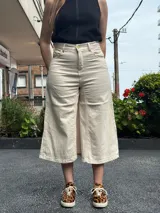 Pantalón capri color crudo, de tiro alto y pierna ancha. Confeccionado en denim con lycra.