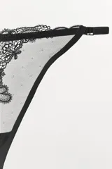 Tanga color dorado semitransparente con detalle de encaje floral en el frente. Cintura elástica fina y ajustable.