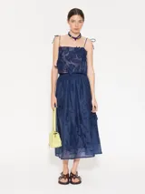 Pollera larga hasta los tobillos, confeccionada en organza color amarillo pálido. Presenta cintura elastizada y flores de tela aplicadas a mano en el delantero.