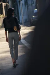 Pantalón gris de vestir, de corte tobillero, con tiro medio, cintura elástica en la parte trasera, bolsillos delanteros y falsos bolsillos traseros.