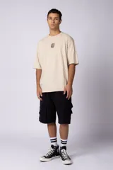 Remera oversize blanca de algodón con un pequeño estampado circular en el pecho que simula un cerebro o un diseño abstracto en espiral, en color negro.