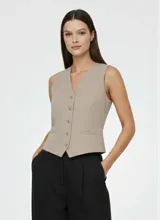 Chaleco sastrero color gris topo melange, de corte ajustado, con escote en V y cierre frontal de botones. Presenta bolsillos falsos en la parte delantera.