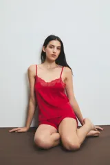 Conjunto de pijama de satén rojo, compuesto por un top con breteles finos y detalle de encaje en el escote, y un short con cintura elástica.