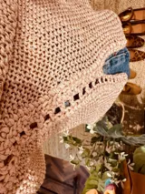 Remera tejida en lurex color rosa con detalles dorados y contornos en crochet, de mangas cortas y cuello en V.