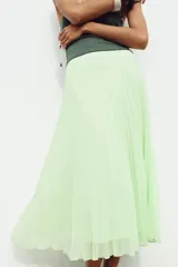 Falda midi plisada color verde menta, de tiro alto, con forro interior y cierre lateral con cremallera oculta.