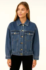 Campera de jean azul con cuello clásico, cierre frontal con botones dorados, bolsillos con solapa abotonada en el pecho y corte holgado.