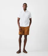 Camisa de hombre de manga corta en lino color blanco, con cuello clásico, botonadura frontal y bolsillo de parche en el pecho. Corte recto.