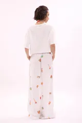Pantalón blanco de corte amplio con estampado de motivos marinos y cintura elástica con cinturón azul con la inscripción 'Verano Mirando al Mar'.
