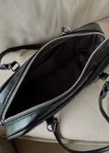 Cartera tipo baguette de cuero sintético color negro con doble asa corta y cierre superior con cremallera.