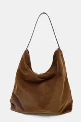 Bolso tipo shopper de gran tamaño, confeccionado en pana marrón con textura acanalada. Presenta un asa de hombro de cuero marrón y un detalle de tira ajustable con hebilla metálica en la parte frontal.