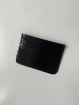 Tarjetero dorado de cuero vacuno con cuatro divisiones para tarjetas y un bolsillo central.