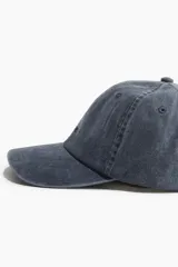 Gorra azul de sarga de algodón con diseño y ojales bordados en la parte superior, trabilla ajustable con hebilla de metal atrás y cinta antitranspirante de algodón.
