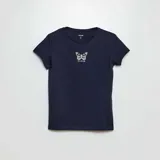 Camiseta azul marino de punto con cuello redondo y mangas cortas. Estampado frontal pequeño con una mariposa y texto.