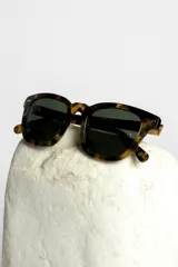 Lentes de sol con montura gruesa color carey y lentes oscuros.