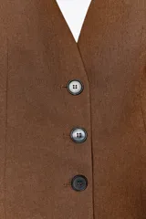 Chaleco marrón con escote en V y cierre frontal con botones. Confeccionado en mezcla de lino.