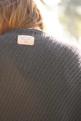 Poncho tejido en lana merino color crudo, con cuello alto y etiqueta de cuero con logo en la espalda.