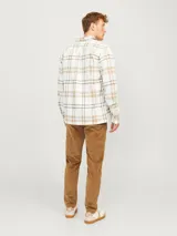 Sobrecamisa a cuadros color blanco, marrón y negro, de manga larga con cierre de botones y bolsillos en el pecho.