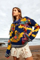 Sweater de lana tejido y bordado a mano con calce holgado, cuello a la base y puños. Diseño con rayas horizontales en azul y amarillo, y bordados de flores multicolores. Talle único, similar a un M/L.