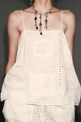 Top blanco de algodón con tirantes finos y bordados combinados a tono.