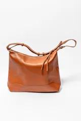 Bolso tipo hobo de cuero color marrón, con correa de hombro ajustable y cierre superior con cordones.
