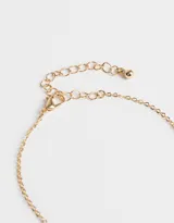 Collar de cadena corta dorada con dije de corazón liso y cierre de mosquetón.
