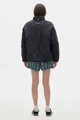 Campera acolchada color crema con cierre frontal y cuello alto. Presenta dos franjas azules en las mangas y ribete azul en el cuello y ruedo.